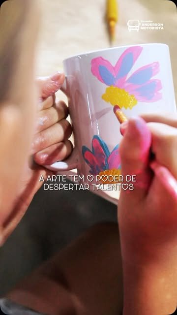 M&atilde;os pintando flores em uma caneca durante a oficina
